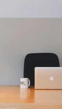 Leeg bureau met een laptop, koffie mok, pennenbakje en lamp.